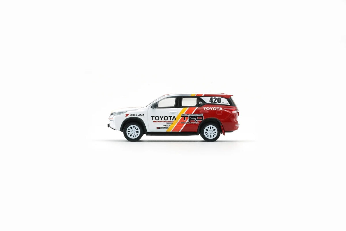 Side view of Toyota Fortuner 2018 TRD Racing 1:64 scale model car showing the yellow and red TRD stripes and white rally wheels (64B0474)