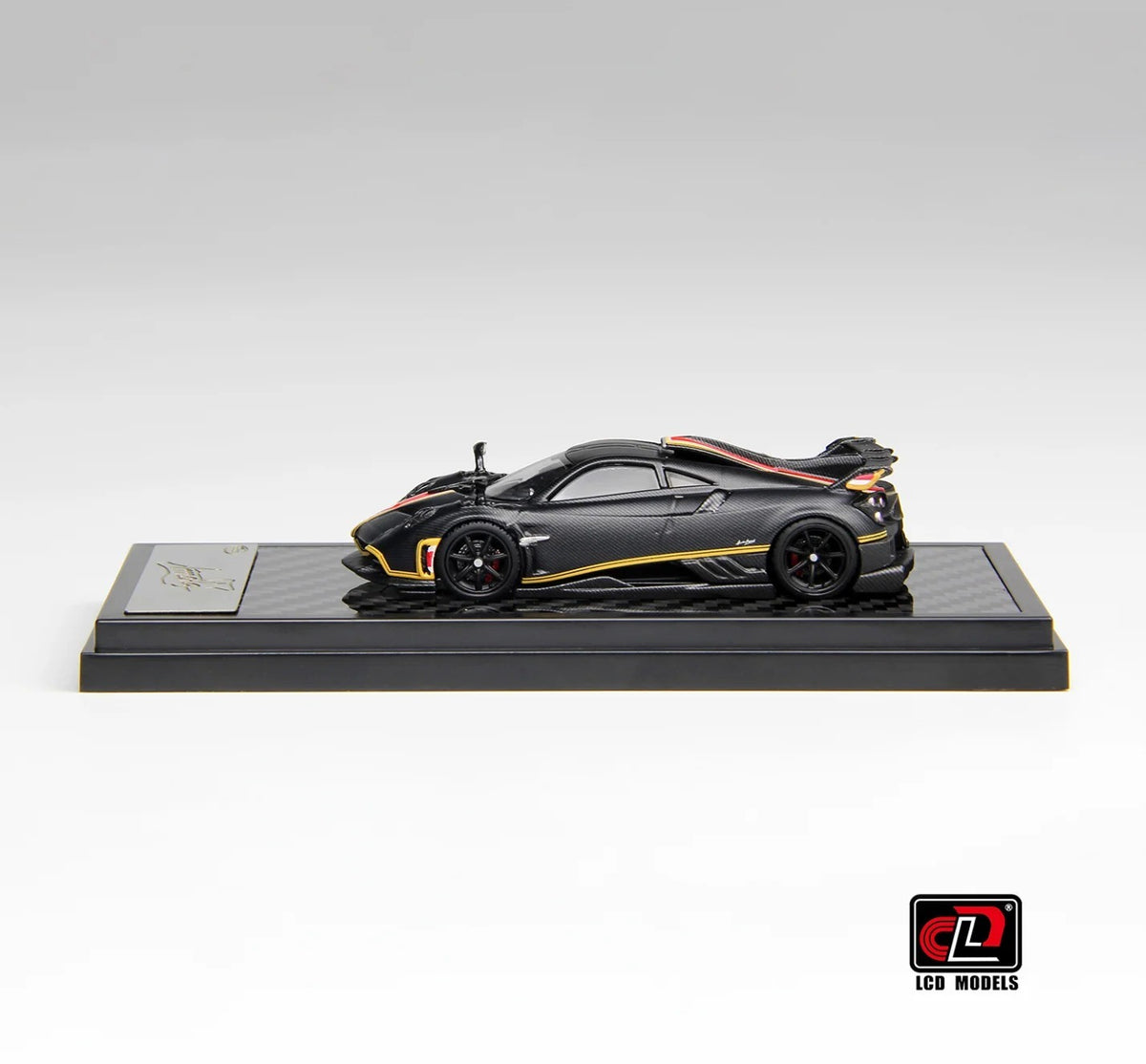 Side profile of Pagani Imola matte black carbon 1:64 scale model car showing the exposed carbon weave and black five-spoke wheels (LCD64041-MBC)