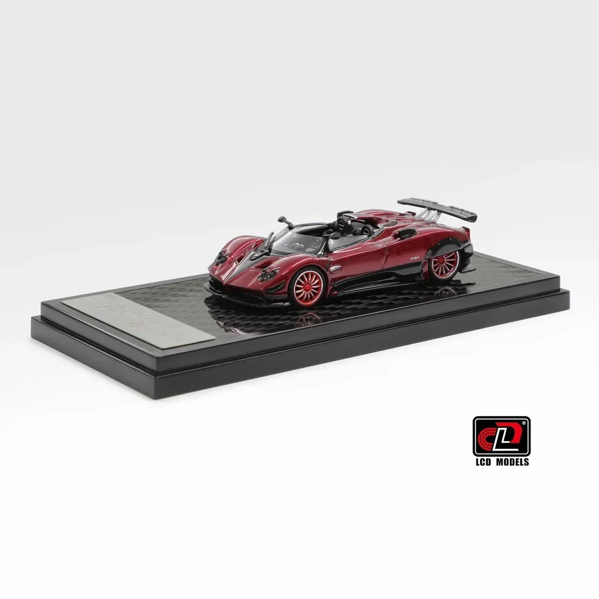 Front three-quarter view of Pagani Zonda HP Barchetta red carbon 1:64 diecast model car by LCD Models on its display base with red multi-spoke wheels (LCD64018-CR)