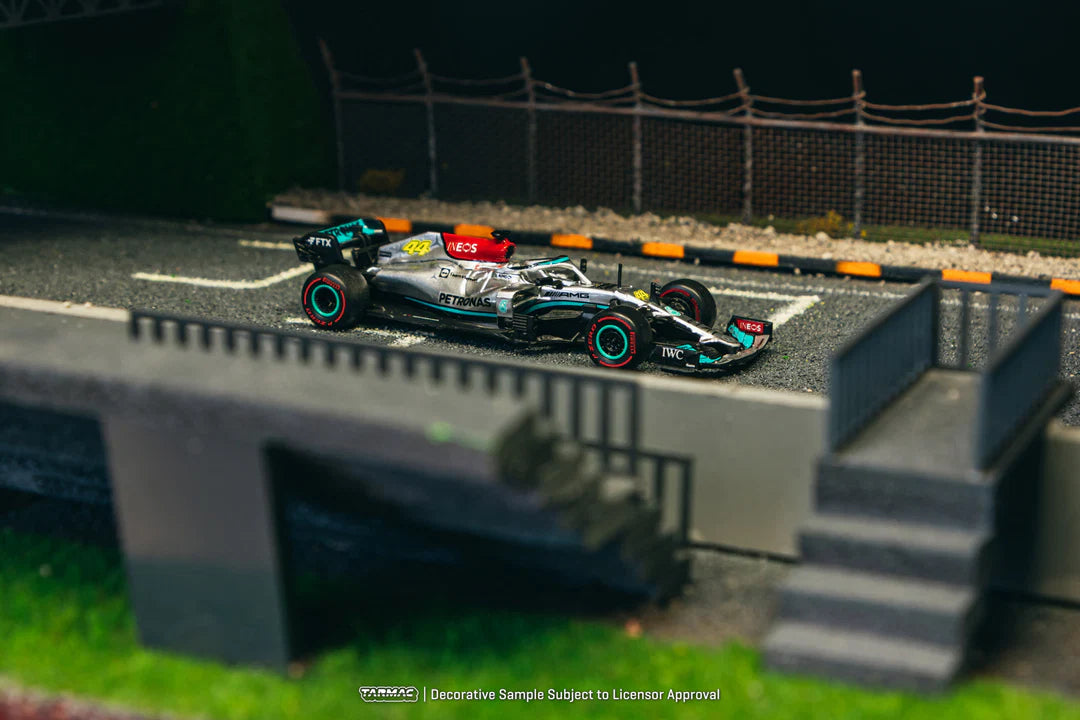 Model racing car on a miniature track with grass and fence in the background