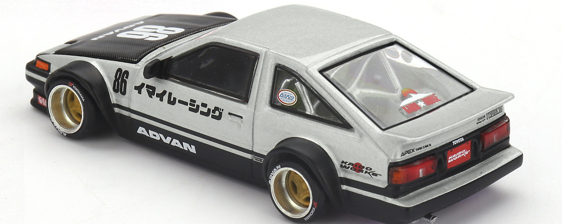 Rear three-quarter view of Toyota AE86 Sprinter Trueno Kaido Street V2 1:64 diecast showing the ducktail wing, roll cage and gold deep-dish wheels (KHMG0218)