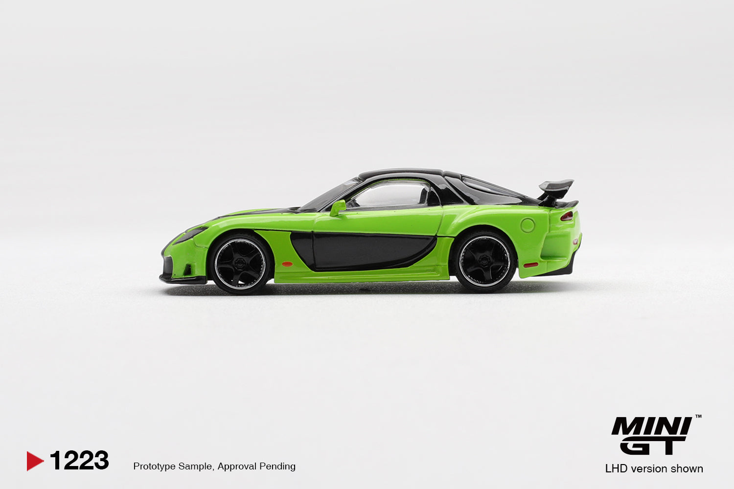 Side profile of Mazda RX-7 VeilSide Fortune7 green 1:64 scale model car showing the smooth Fortune widebody flanks and dark multi-spoke wheels (MGT01223)
